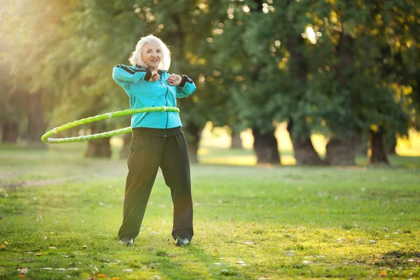Здоровые пожилая женщина делает упражнения в природе — стоковое фото