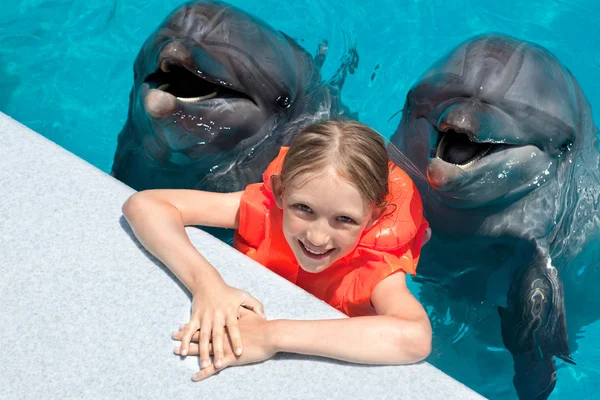 Niña feliz sonriendo con dos delfines en la piscina — Foto de Stock