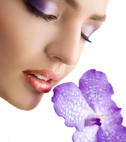 Крупним планом красиве ніжне жіноче обличчя з фіолетовою орхідеєю — стокове фото