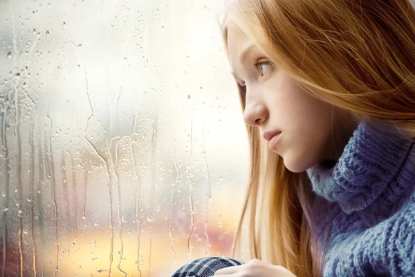 Dia chuvoso: Menina olhando através da janela — Fotografia de Stock