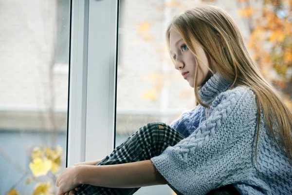 Día lluvioso: Niña sentada en la ventana —  Fotos de Stock