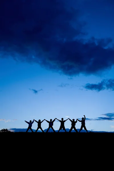 Silhouetten von sechs Kindern, die zusammen im Sonnenuntergang stehen — Stockfoto