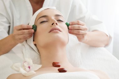 Spa salonu: genç güzel kadın olan yüz masaj Ston ile