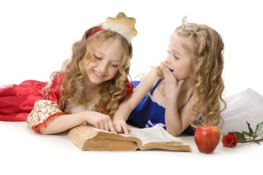 Two beautiful little princesses reading a magic book clipart