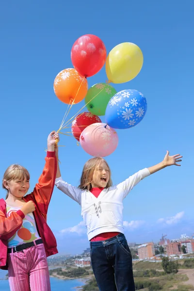 Two Girl Holding Colorful Helium Balloons in the Sky — Stock Photo, Image