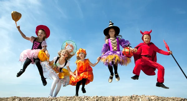 Vijf Halloween kinderen springen op de blauwe hemel — Stockfoto