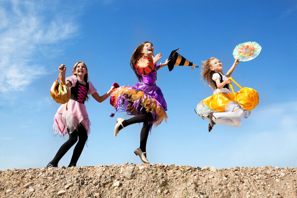 Three Cute Little Witches Jumping with Bags