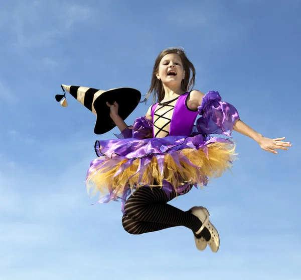 Šťastná malá čarodějnice skákání na modrou oblohu — Stock fotografie