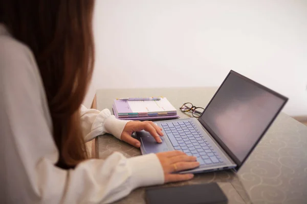 Evde bilgisayarla çalışan mutlu ve serbest bir genç kadın. İnternette okuyan çekici bir iş kadını, dizüstü bilgisayar, internet sörfü bilgisi veya internet mağazasından alışveriş yapıyor. Genç kahverengi saçlı kadın online alışveriş yapıyor..