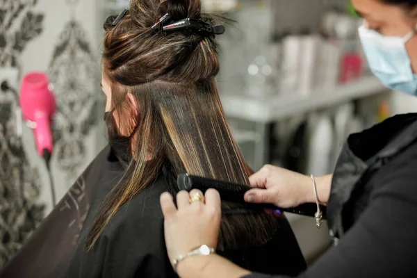 Woman with face mask getting a fresh style at a hair salon. Woman getting a hair wash. Hairdressing concept. Hairdresser cutting and styling a woman in her shop