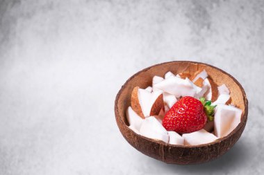 Bir kase hindistan cevizi ve çimento kaplı çilek. Tabakta hindistan cevizi malzemesi var. Sıfır atık hindistan cevizi kasesinde vejetaryen organik atıştırmalık. Mesaj için yer var. Mesaj için yer. Vejetaryen Kafe Afişi