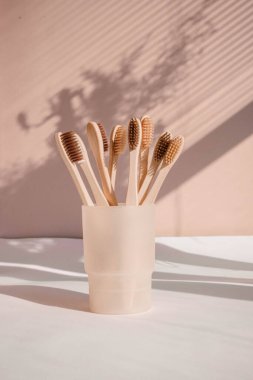 Pastel arka planda çiçek gölgeli sıfır atık bambu diş fırçası. Yüksek kalite fotoğraf