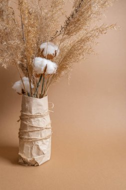 Vazodaki bej arka planda bir buket pampa otu ve pamuk çiçeği. Boho tarzı buket. Eko çiçek kompozisyonu. Yüksek kalite fotoğraf