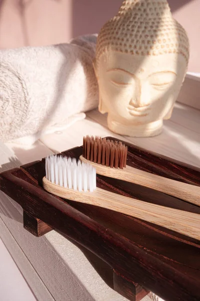 White Buddha bust on pastel pink background decorated with shades. Zero waste bamboo toothbrush. Spa asian style. Relax mood. Yoga background. Eco friendly . High quality photo
