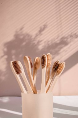 Pastel arka planda çiçek gölgeli sıfır atık bambu diş fırçası. Yüksek kalite fotoğraf