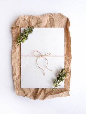 Beyaz çarşaf, çiçek dallarıyla buruşmuş kağıdın üzerinde yatıyor. Düz çizgi kağıt şablonu oluşturur 