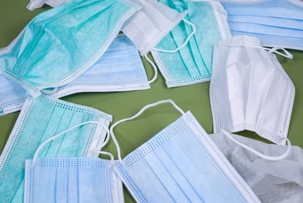 Different surgical masks on light green background.