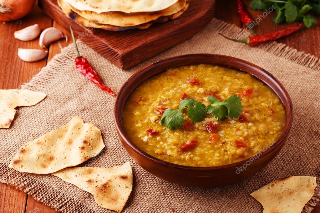 Thick indian red lentil soup with cilantro served with indian flat
