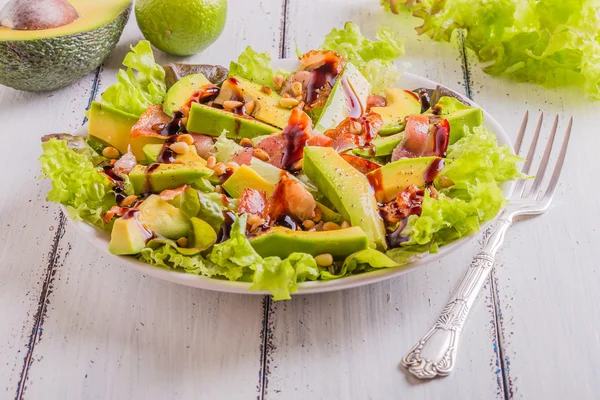 Avocado salad with fried bacon and pine nuts