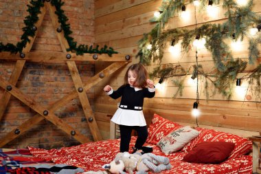 Küçük kız büyük bir yatakta dans ediyor.