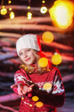 Kız model elinde parlak bir çelenk tutuyor.