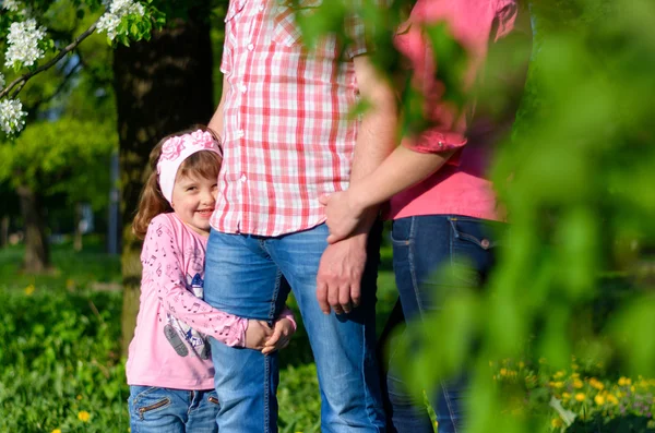 Ein Mädchen sammelt die Feldblumen in einem Strauß sitzt neben den Eltern — Stockfoto