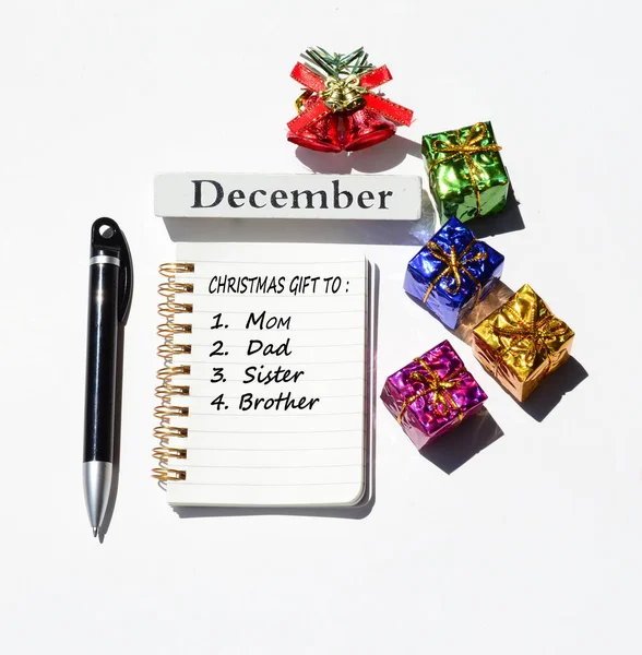 Christmas gift to mum dad sister brother written on notepad with christmas decorations background. Merry Christmas