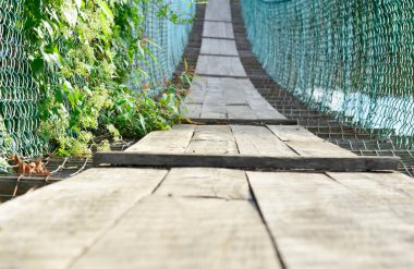 Asma köprü yeşil çalılarla dolu ve zincirli tel örgülerden yapılma Penampang, Borneo, Sabah, Malezya kırsalında yol için kontraplaktan yapılmış.. 