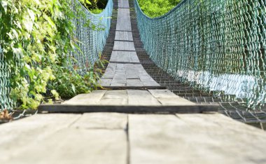Asma köprü yeşil çalılarla dolu ve zincirli tel örgülerden yapılma Penampang, Borneo, Sabah, Malezya kırsalında yol için kontraplaktan yapılmış.. 