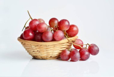 Beyaz arka planda eski bir sepetteki kırmızı üzüm