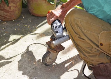 Kaynak makinesi olan bir işçi etrafta uçuşan kıvılcımları olan tekerlekleri tamir ediyor.
