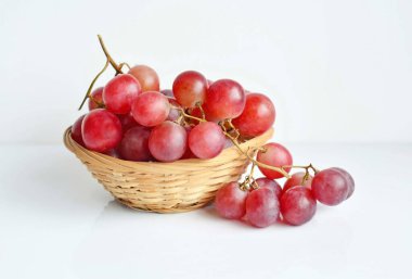 Beyaz arka planda eski bir sepette kırmızı üzüm. Sağlıklı yeme kavramı 