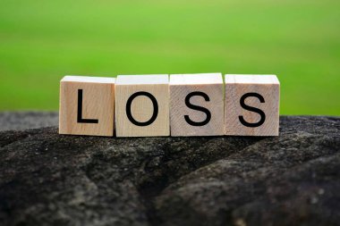 Büyük taşın tepesindeki ahşap küp bloktaki bulanık yeşil arkaplanlı kayıp metin