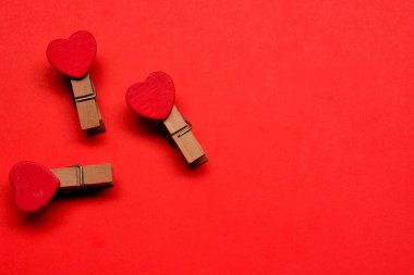 Kırmızı kağıt arka planda kırmızı kalp şeklinde bir mandal. Sevgililer Günü konsepti