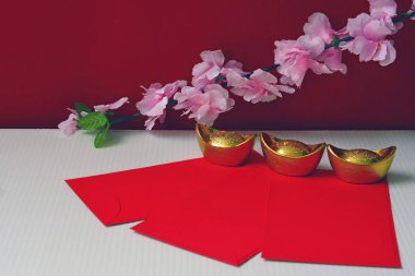 Çin Yeni Yıl Festivali süslemeleri güm güm ya da kırmızı paket ve altın külçeler veya kırmızı arka planda erik çiçekleri açan altın topak iyi şans, zenginlik, para akışı.