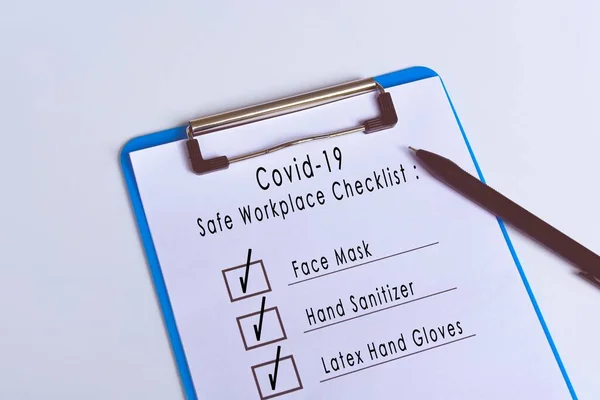 Covid-19 safe workplace checklist attached on blue clip board and pen. Workplace safety concept