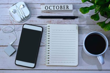 Üzerinde bir fincan kahve, akıllı telefon, not defteri, müzik çalar ve ekimde yazılmış beyaz küp bloğu olan ahşap masa resmi. Metin kullanımı için