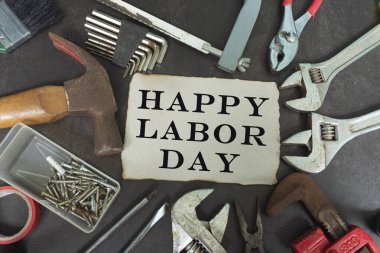 Sarı not defterine yazılmış mutlu çalışma günü metinleri. Onarım ekipmanları ve karanlık arka planda kullanışlı araçlar.