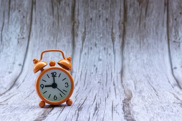 Orange old retro style alarm clock on wooden background