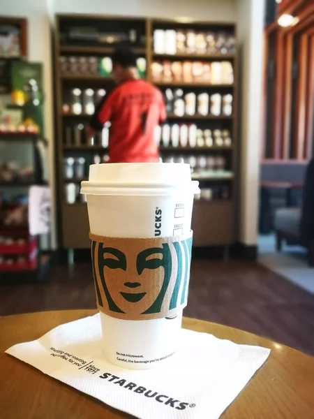 Kawiarnia Starbucks, Kota Kinabalu, Malezja - 13 kwietnia 2021: Biały jednorazowy kubek Starbucks z zamazanym tłem sklepu z pamiątkami — Zdjęcie stockowe
