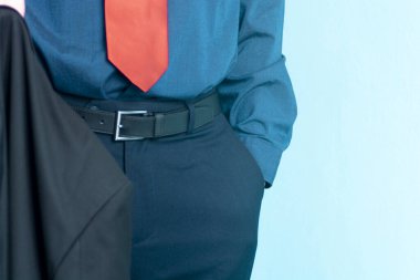 Mavi arka planda bir eli cebinde duran ve ceketini tutan bir iş adamı. İzole edilmiş