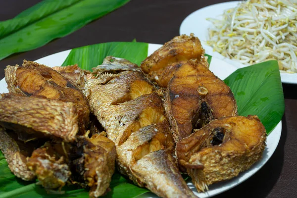 Ikan goreng di piring dengan daun hijau — Stok Foto