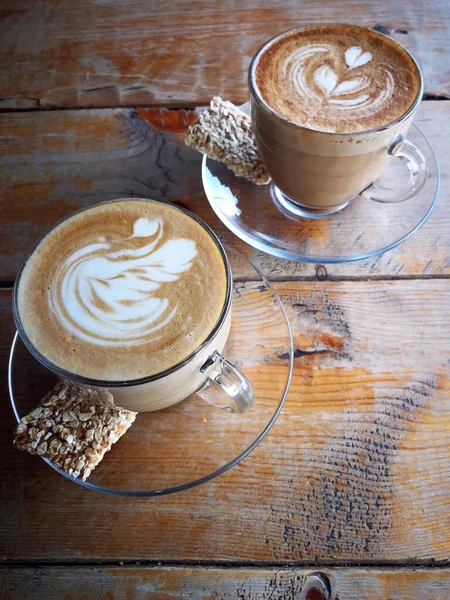 Káva ve skleněném šálku se sušenkami na dřevěném stole v kavárně — Stock fotografie