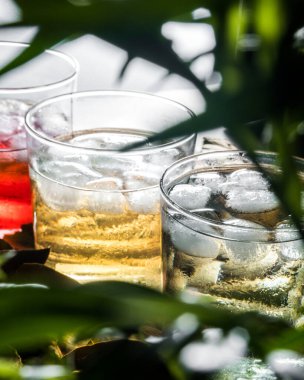 Kırmızı, sarı ve yeşil sıvılar ve buzlarla dolu üç bardak.