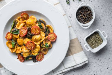 Domates soslu ve fesleğenli dana makarnası, kiraz domates ve baharatla süslenmiş.