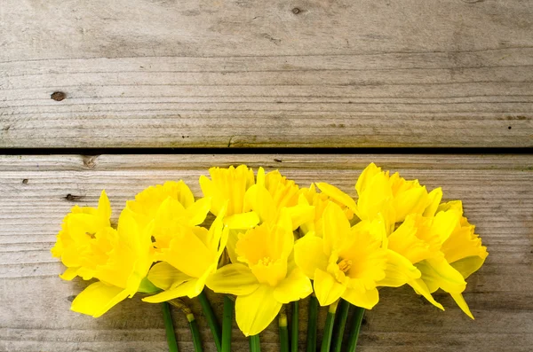 Narcisos amarelos na mesa de madeira — Fotografia de Stock
