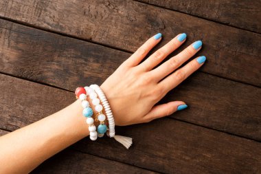 Mavi tırnaklı ve bilezik takan genç bir kadın. Üst görünüm