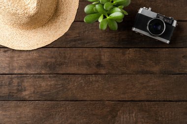 Hasır şapkalı fotoğraf makinesi ve ahşap masada küçük bir çiçek. Seyahat arkaplanı kavramı