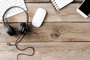 Kulaklıklar ve ofis aksesuarları kopyalanmış ahşap masada. Çağrı merkezi kavramı