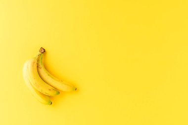 Sarı arka planda bir sürü taze muz ve kopyasal alan. Üst görünüm